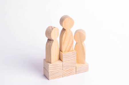 Three wooden figures of a man stand on the podium of the winners. The concept of victory, business competition and competition among employees. Olympiad and Paraolympic Games, Universiadeの写真素材