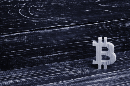 Wooden Bitcoin on a background of black boards. Crypto currency, blocking technology. The collapse and rise in the cost of bitcoin. Mining farms, miners, stock exchange crypts. Decentralized moneyの写真素材