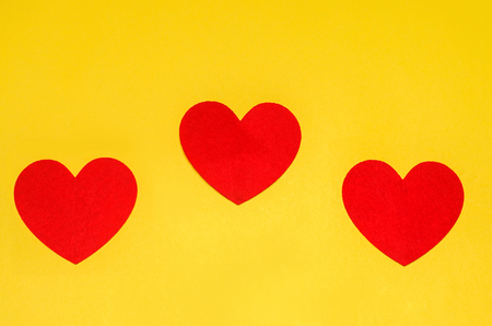 three red hearts on a yellow background, the concept of love, the day of St. Valentine's Dayの写真素材
