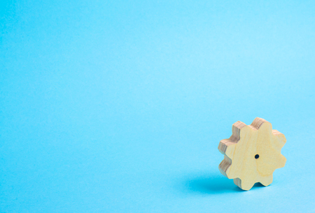 A wooden gear in the corner on a blue background. Minimalism, a place for text. Technology and business, an uncommon simple backgroundの写真素材