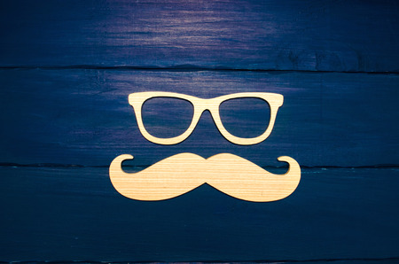 Hipster  concept. Wooden mustache and wooden glasses on a blue background

の写真素材