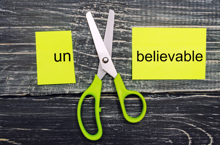 scissors cut the word unbelievable. concept believable. cuts the word "un. "I can, goal achievement, potential, overcomingの写真素材