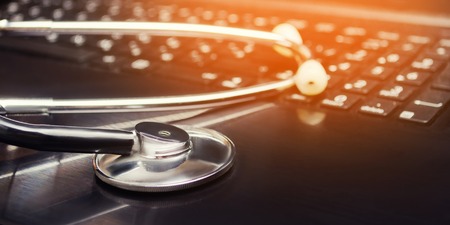 Healthcare and medicine or computer antivirus protection and repair maintenance service concept: macro view of stethoscope on business office laptop notebook keyboard. online treatmentの写真素材