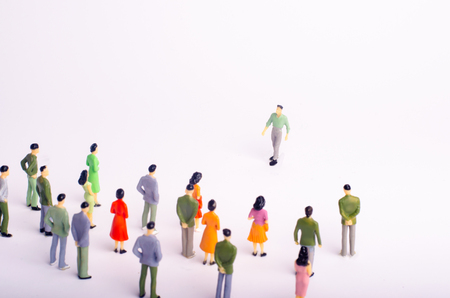 The crowd is looking at the man who comes towards her on a white background. The man is approaching a group of people. Leader of the team, messiah, leader. A new person at work. Selective focusの写真素材