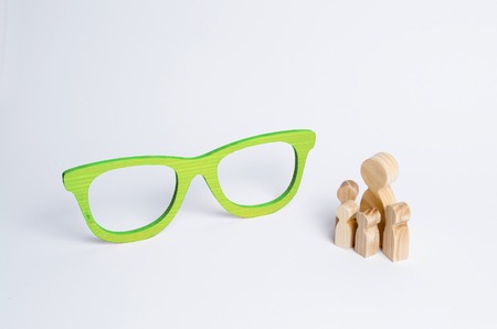 A crowd of people looks at the sculpture of huge green glasses. Concept of education and wisdom of older generations, modern art. Preschool, school, university. Science and education Selective focusの写真素材