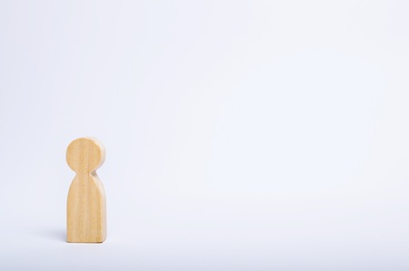 A lone wooden human figure stands on a white background. A person is waiting, standing and waiting. Style of minimalism, space for textの写真素材