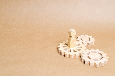 The person stands on a wooden gear. The concept of technology and industry, the think process. Part of a large complex mechanism. Business process, institution work. Business team, team workの写真素材