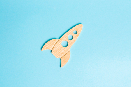 A wooden rocket on a blue background. The style is retro. The concept of space flights and achievements in high technologies. Business take off and grow. Space tourism. launching satellitesの写真素材