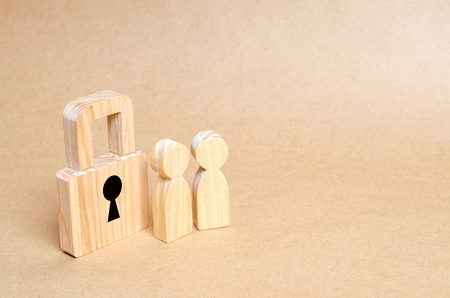 Wooden people with padlocks. Two people with a lock. Security and safety, collateral, loan for a mortgage. Confiscation of property for debts. Safety and alarm system. Security service.の写真素材