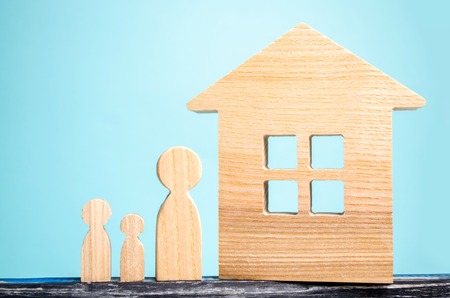 concept of real estate, housing for the family, buying and selling of quarters, apartment rental, mortgage, people figurines and house on a blue backgroundの写真素材