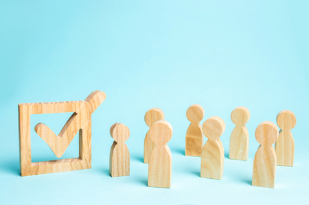 human figures stand together next to a tick in the box. The concept of elections and social technologies. Volunteers, parties, candidates, constituency electorates. Human rights. Selective focusの写真素材
