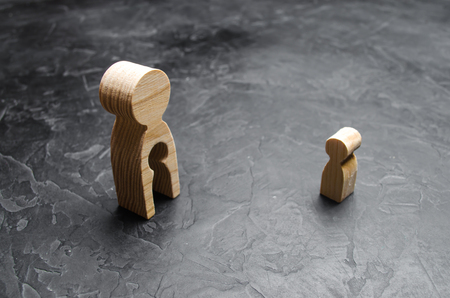 A wooden figure of a man with a void in the form of a child inside the body stands and looks at the child.の写真素材
