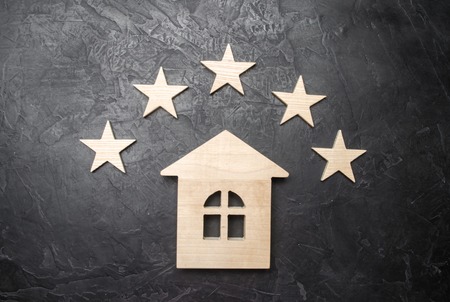 Wooden house and five stars on a gray background. Rating of houses and private property. Buying and selling, renting apartments.の写真素材