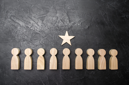 A star above a person who stands in a row among other people. Wooden figurines.の写真素材