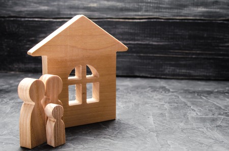 Wooden figures of the family stand near a wooden house. The concept of finding a new home, moving.の写真素材