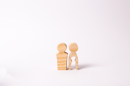 Wooden figures of a man and a woman with a void inside the body in the form of a child. Infertility in a couple. Loss of a single child. Medical problems. The couple wants to have a baby.の写真素材
