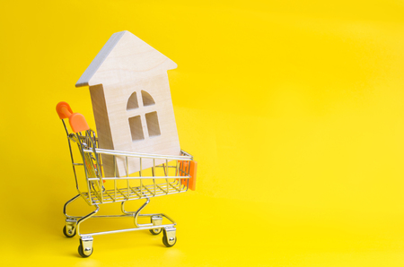 Property investment and house mortgage financial concept. buying, renting and selling apartments. real estate. Wooden house in a shopping basket. credit, affordable housing for young families. copy spaceの写真素材