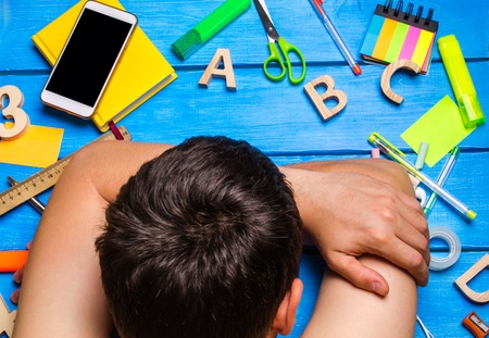 A student is asleep in the workplace, a creative mess. The student is lazy and does not want to learn. The guy is tired and asleep on the table. The concept of education and learning process. Lessonsの写真素材