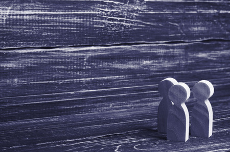 Three wooden human figures stand together. Social concept, family, team, friends, brothers and sisters. Space for text.の写真素材