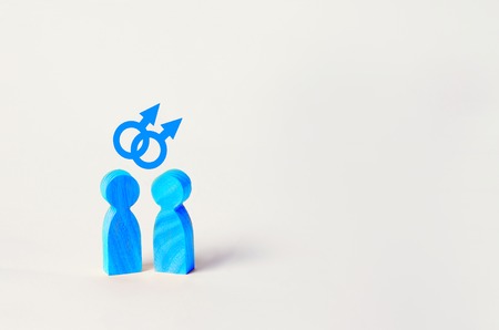 two blue wooden figures of people stand on white background. two persons of homosexual orientation. the concept of relations between gays and representatives of gender minorities. Lifestyle. copy spaceの写真素材