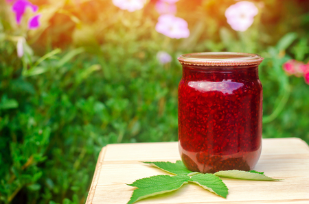banks with fragrant homemade raspberry jam in the garden. summer harvest. sweet food. food stock for the winter. countryside, outdoor. natureの写真素材