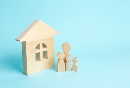 Family is standing near the house. Wooden figures of persons stand near a wooden house. The concept of a couple in love, cohabitants, parents, buyers and sellers at home. They live in the houseの写真素材
