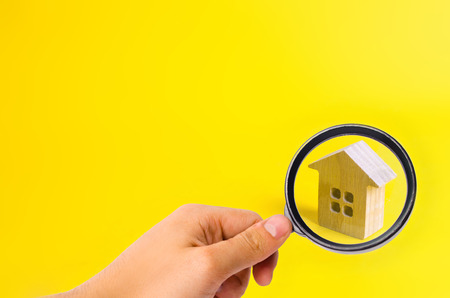 A small wooden house stands on a yellow background. The concept of buying and selling real estate, renting. Search for a house. Affordable housing, credit and loans. Investments in businessの写真素材