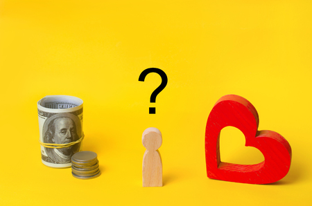 a wooden man chooses between money and love. Passion versus profit. Family or career choice. family psychology.の写真素材