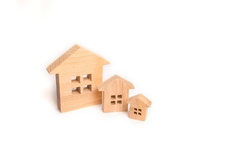 Three wooden houses stand in a row in descending order on a white background. The concept of buying...
