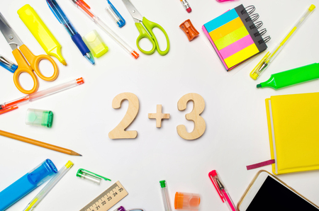 mathematics. numbers 2 plus 3 on the school desk. concept of education. back to school. stationery. White background. stickers, colored pens, pencils, scissors. view from above. flat lay.の写真素材
