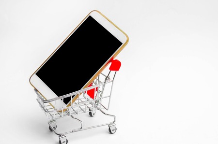 mobile phone in a supermarket trolley. buying and selling a smartphone. online store. consumer credit. isolated white backgroundの写真素材