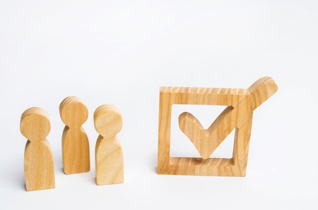 three people are standing together next to a tick in the box. The concept of elections and social technologies. Volunteers, parties, candidates, constituency electorates. Human rights.の写真素材