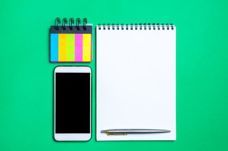 phone, notebook, pen and sticky stickers on the school desk. back to school. green background. place for text. stationery. copy space. view from above. flat layの写真素材