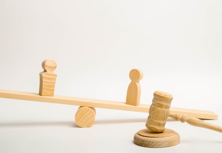 Two people on the scales and a judge hammer on a white background. The concept of litigation. The...