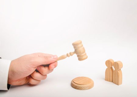 Two men and a hammer of the judge. The trial of cases in court, the resolution of a dispute between two people. Business relations, ascertaining the ownership of property. Litigation.の写真素材
