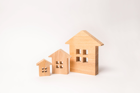 The concept of buying and selling real estate. Residential area, rental and investment in real estate. Three wooden houses stand in a row in descending order on a white background.の写真素材