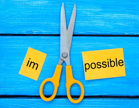 Impossible Is Possible Concept. Card with the text impossible, scissors cut a word to them. Success...