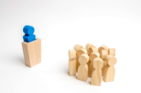 The leader from the rostrum speaks a speech addressing a crowd of people. Business concept of leader and leadership qualities, crowd management, political debate and elections. Business management.の写真素材