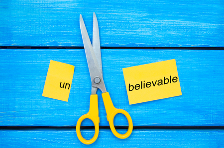 scissors cut the word unbelievable. concept believable. cuts the word "un. "I can, goal achievement, potential, overcomingの写真素材