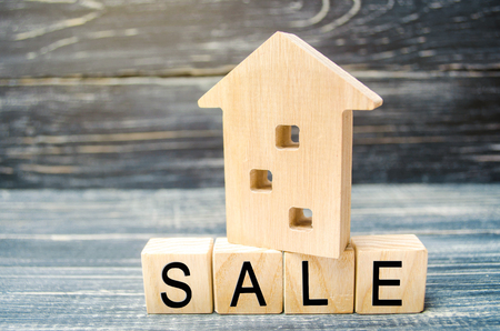 wooden house on a black background with the inscription sale. sale of property, home, real estate. affordable housing. place for text. copy spaceの写真素材
