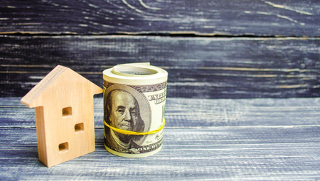 wooden house and dollars on a blue background. concept of real estate. buying, selling, renting. credit for property. sale apartment. mortgage. affordable housing for a young family. loanの写真素材