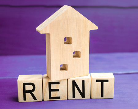 Wooden house on a purple background with the inscription rent. Rental of property, apartments. services of a realtor. affordable housing, rental prices. place for text. copy spaceの写真素材