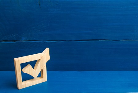 Election of the President or Government. Democracy, development, civil initiative. A wooden checkmark in the box on a blue background. The concept of suffrage, voting in elections.の写真素材
