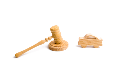 Wooden figurine of a car in the hammer of a judge on a white background. Minimalism. Purchase and sale of the car. The trial, confiscation of the machine. Recognition of ownership.の写真素材