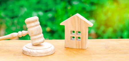 A miniature wooden house and a hammer of the judge. Auction to buy / sell a house. Forced eviction and confiscation. Clarification of ownership of property. Concept settlement of litigation. Courtの写真素材