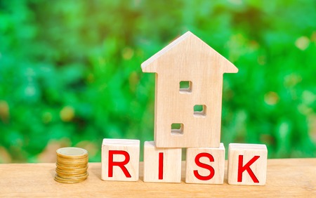 wooden house and cubes with the word risk. The concept of risk, loss of real estate. Property insurance. Loans secured by home, apartment. Financial risks, litigation.の写真素材