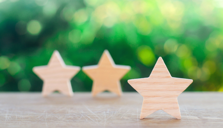 Three wooden stars on a green bokeh background. The concept of the rating of hotels and restaurants, the evaluation of critics and visitors. Quality level, good service. selective focusの写真素材