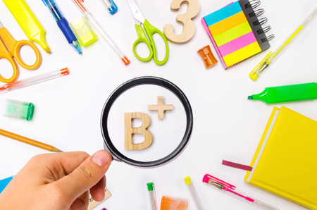 school supplies in the school desk, stationery, school concept, blue background, creative chaos, space for text, markers, pens, notepad, stickers. the average rating point. good class. B plusの写真素材