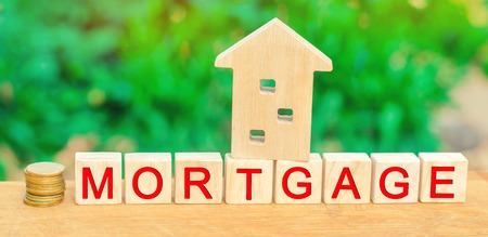Miniature house and money. Wooden blocks and the inscription "mortgage". credit for property / apartment. Business loans for real estate concept. mortgage insuranceの写真素材