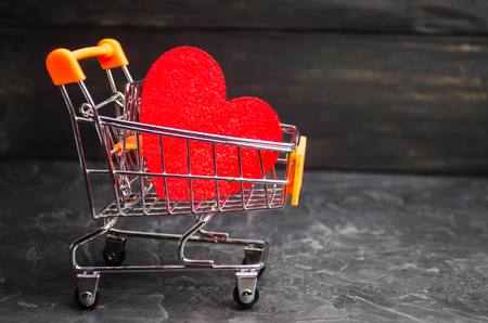 red heart in the supermarket trolley. concept of buying love. Valentine's Day. yellow background. Love of shopping. Favorite store. Buy love and happiness. Intimate services for moneyの写真素材